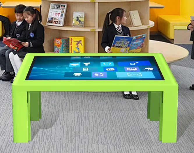 Green interactive touch table used by children in a classroom